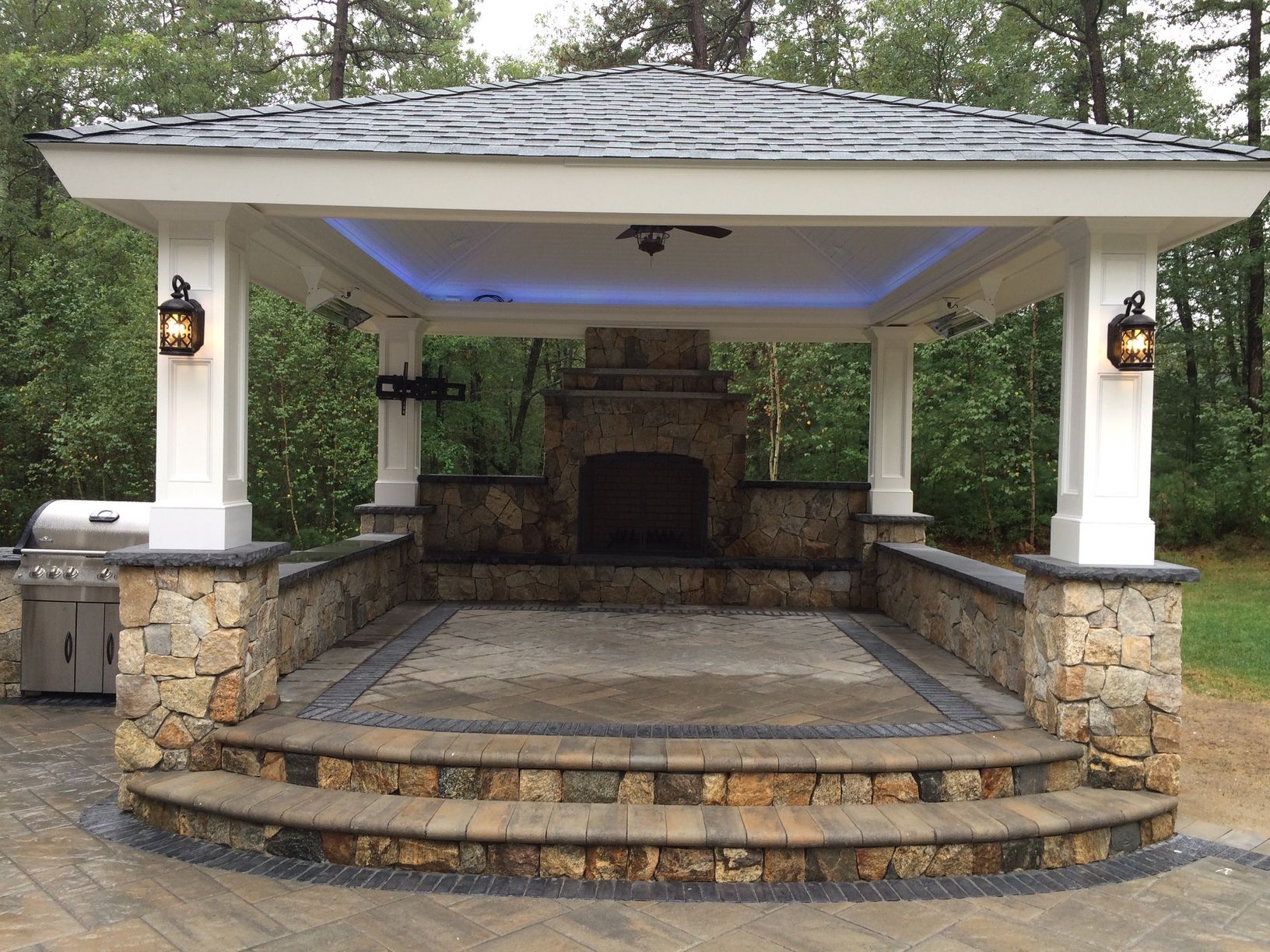 A gazebo with a fireplace in the middle of it