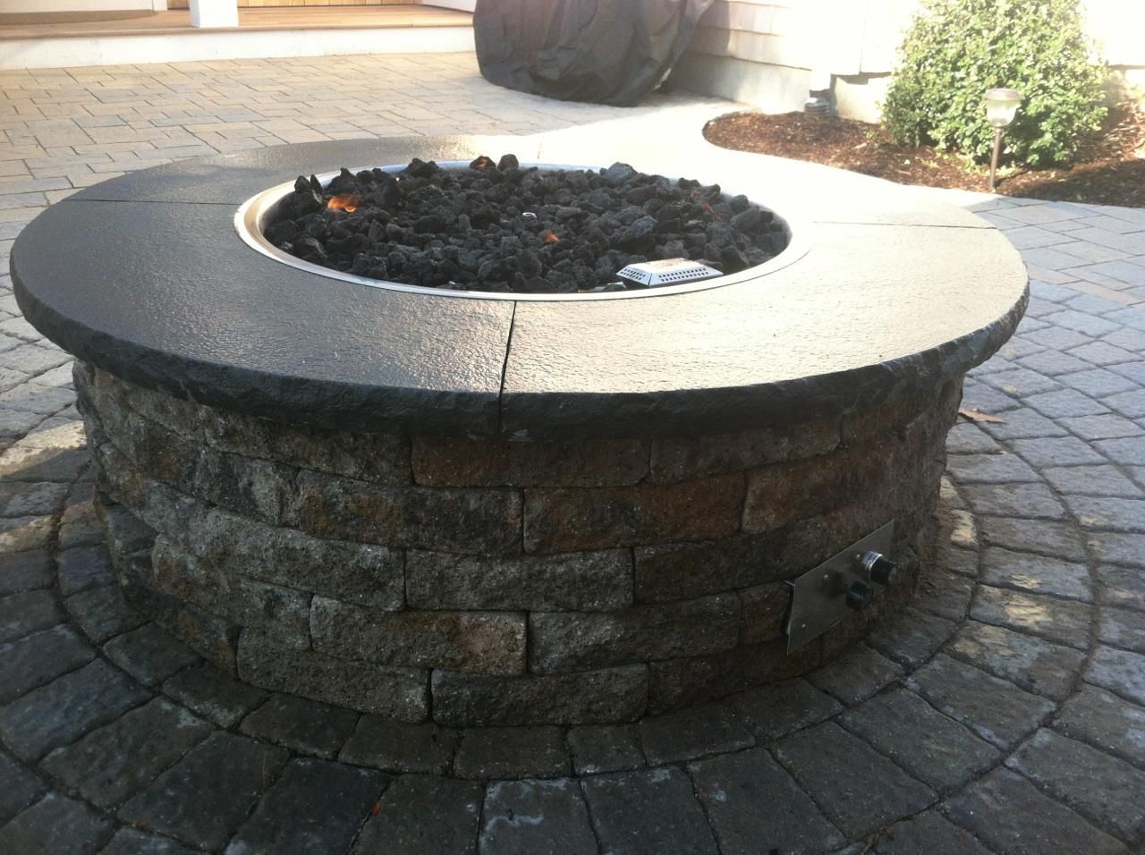 A fire pit is sitting on a brick patio
