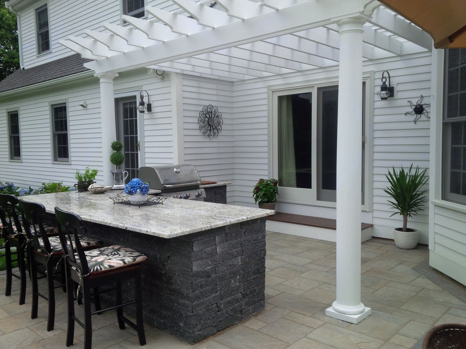 A patio with a pergola and a table and chairs