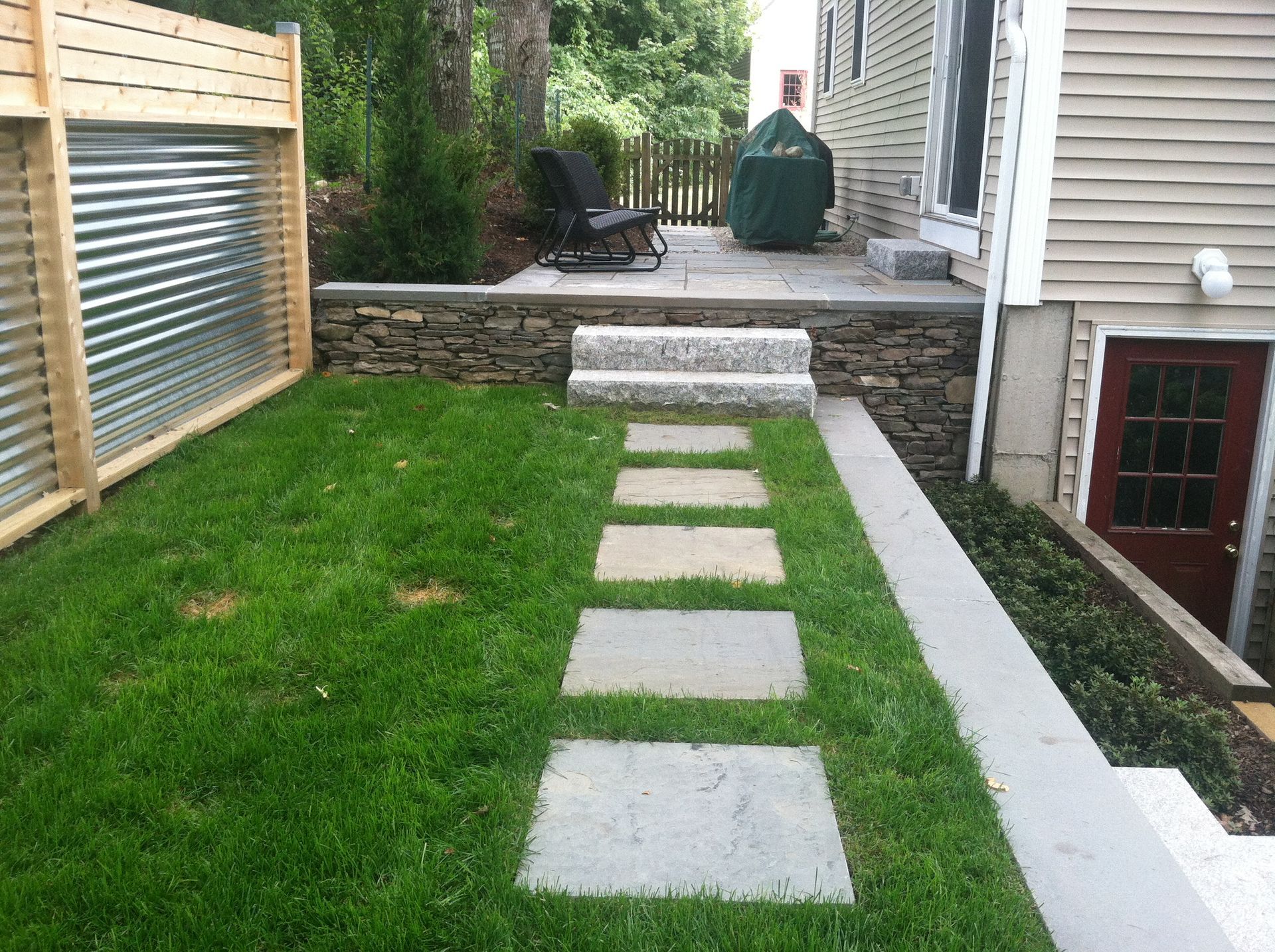 A backyard with a stone walkway leading to a patio