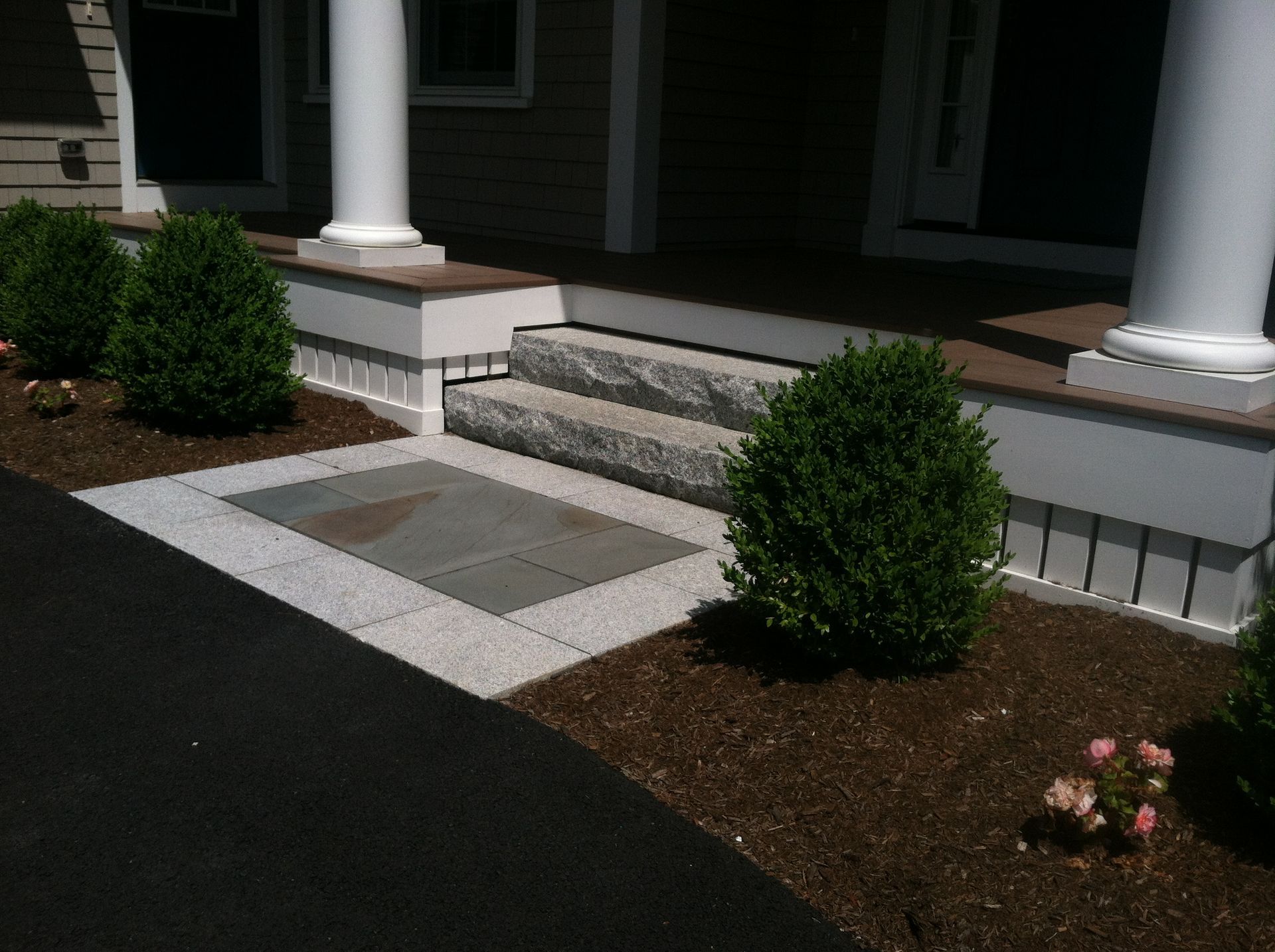A stone walkway leading to a porch of a house
