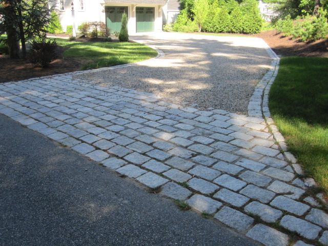 A driveway with a brick walkway leading to a house
