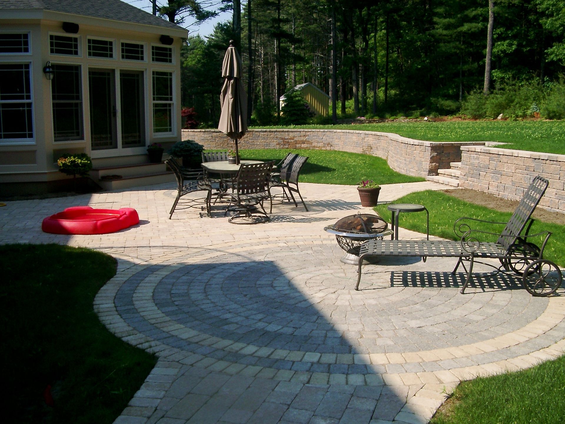 A patio with chairs tables and umbrellas in front of a house