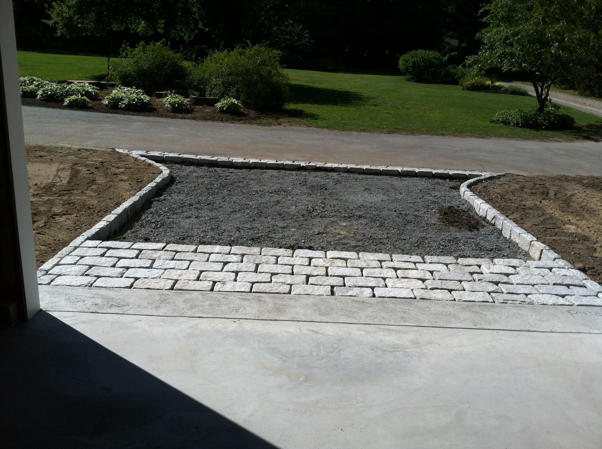 A brick walkway leading to a gravel driveway