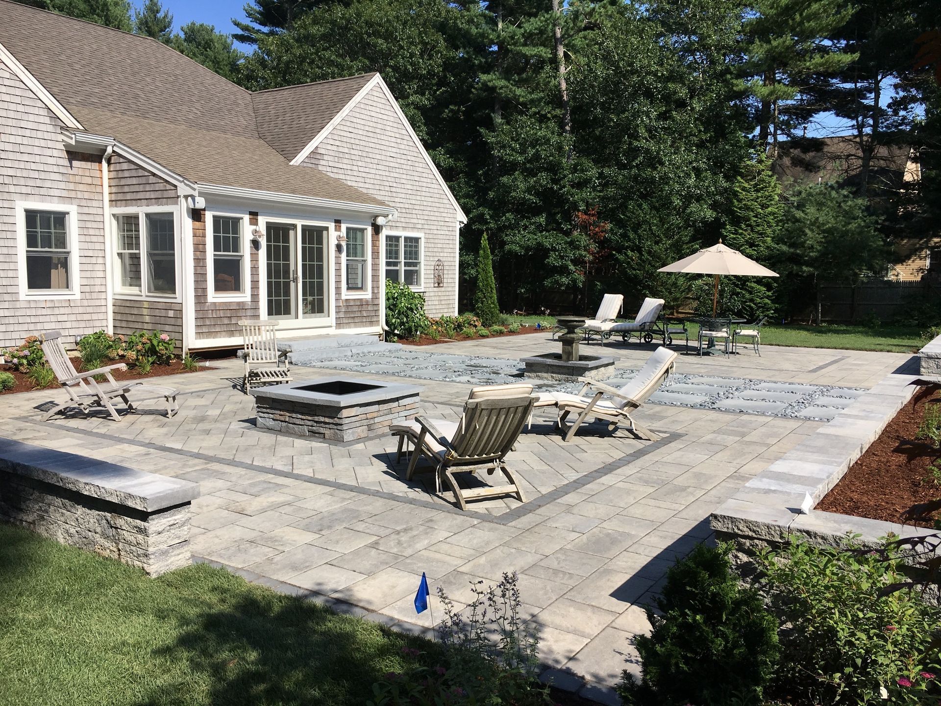 A large patio with a fire pit and chairs in front of a house