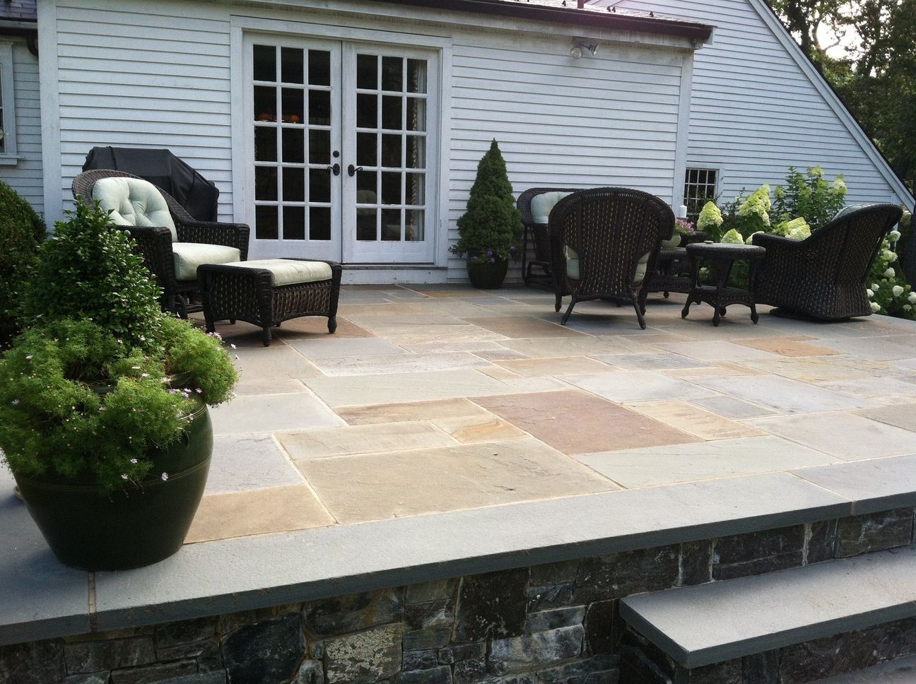 A patio with chairs and a table in front of a house