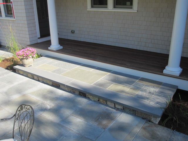 A patio with chairs and flowers in front of a house