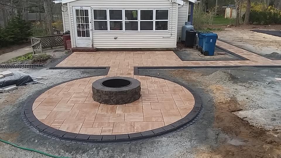 A fire pit is in the middle of a patio in front of a house