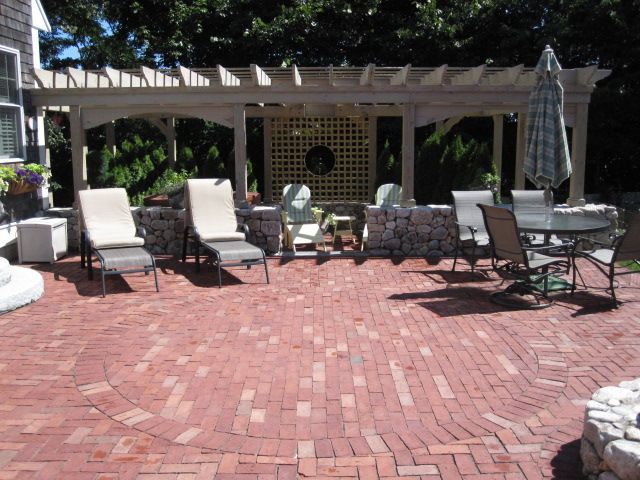 A brick patio with chairs and a table under a pergola
