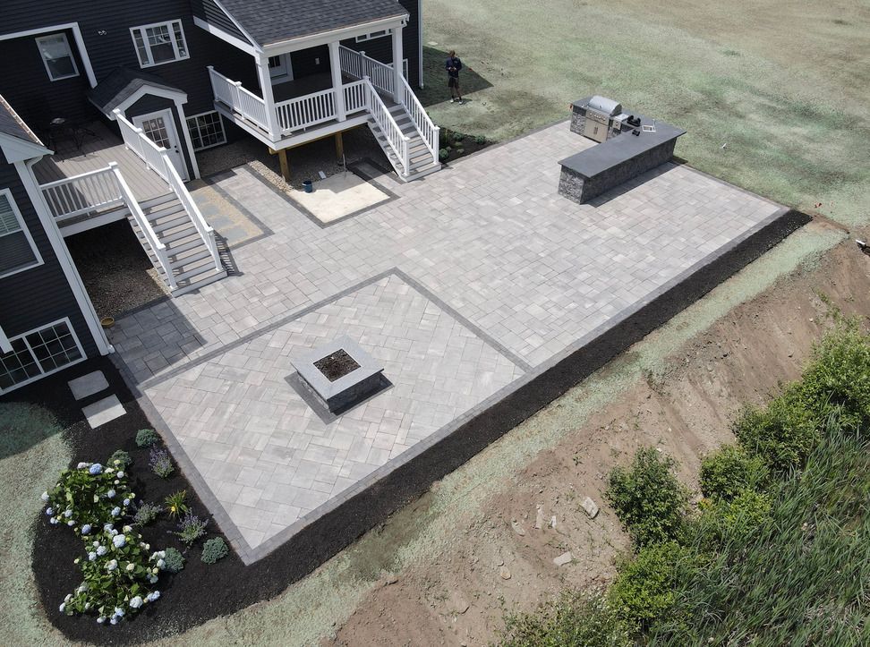 An aerial view of a patio with a fire pit in the middle of it in front of a house.