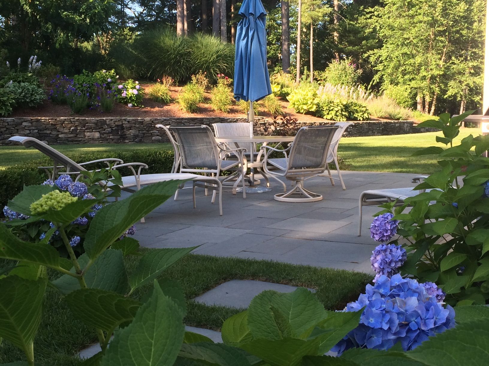 A patio with a table and chairs and a blue umbrella