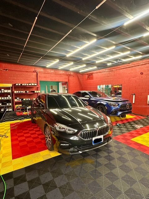 Two sports cars in a red garage with checkered floor and bright ceiling lights