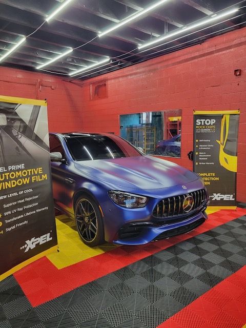 Blue Mercedes-Benz SUV in a red auto detailing shop with marketing banners and checkered floor