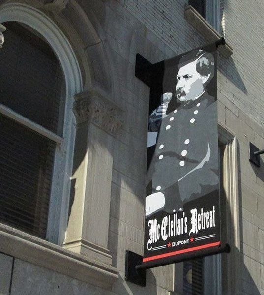 Banner for McClellan's Retreat, featuring a portrait of General McClellan, on a brick building facade.