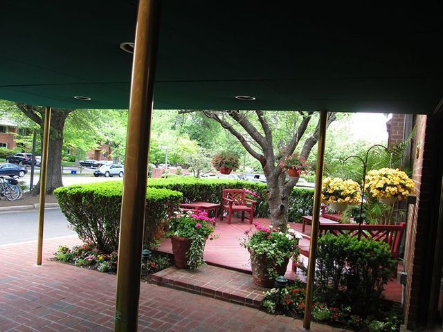 Outdoor patio with red brick, plants, tables, and green awning.