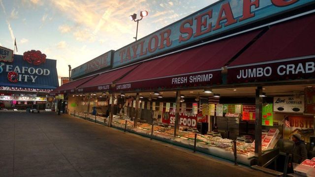 Seafood market exterior with red awnings, signs for fresh shrimp and jumbo crab, setting at dusk.