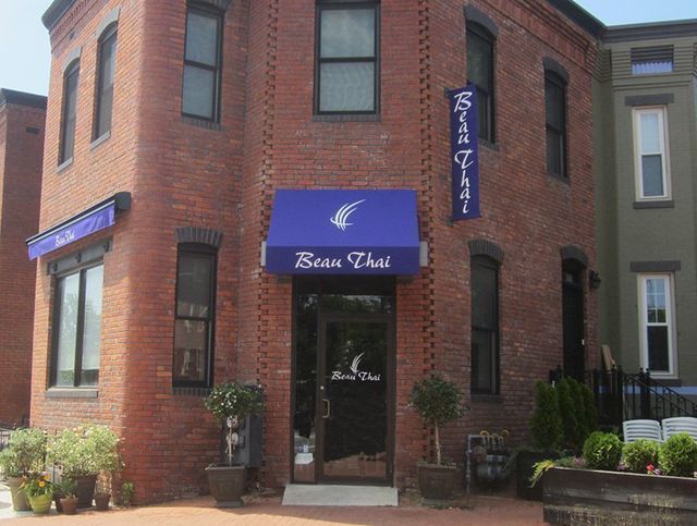 A brick building with a blue awning that says 