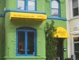 Green building with blue-framed windows, two yellow awnings, and 