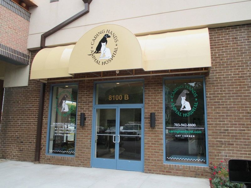 Exterior of an animal hospital with awning and logo, brick building, double doors, and windows.