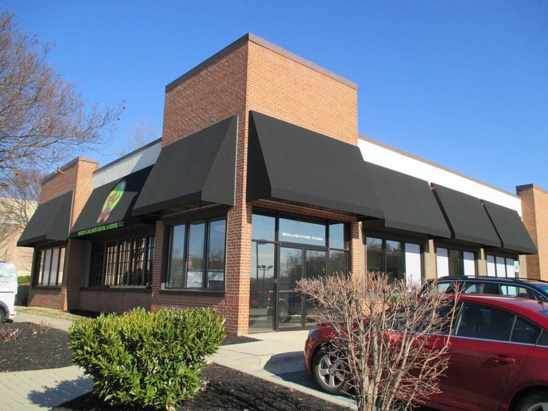 A brick building with black awnings, glass windows, and a clear blue sky.