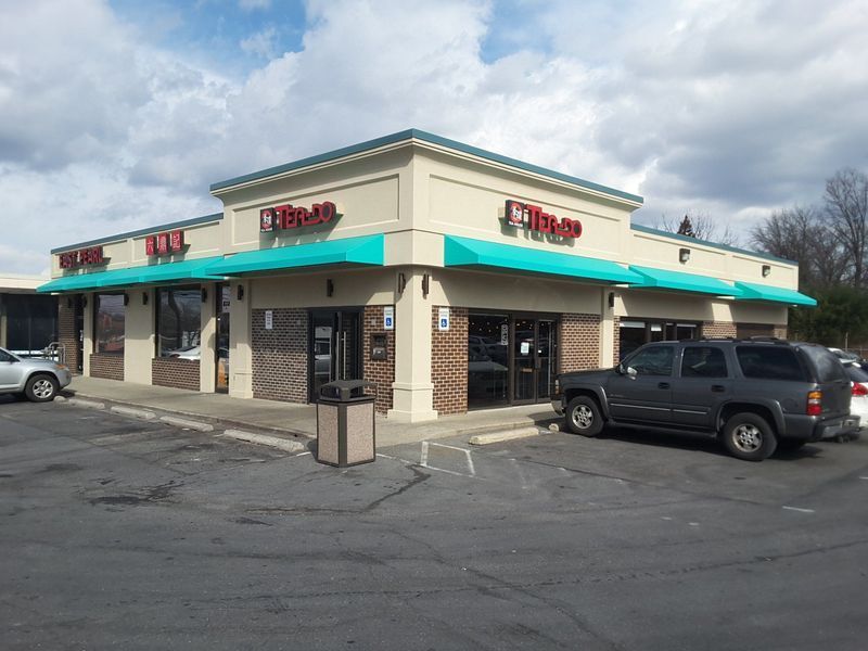 Exterior of a Tim's restaurant with a teal awning and a gray SUV parked outside.