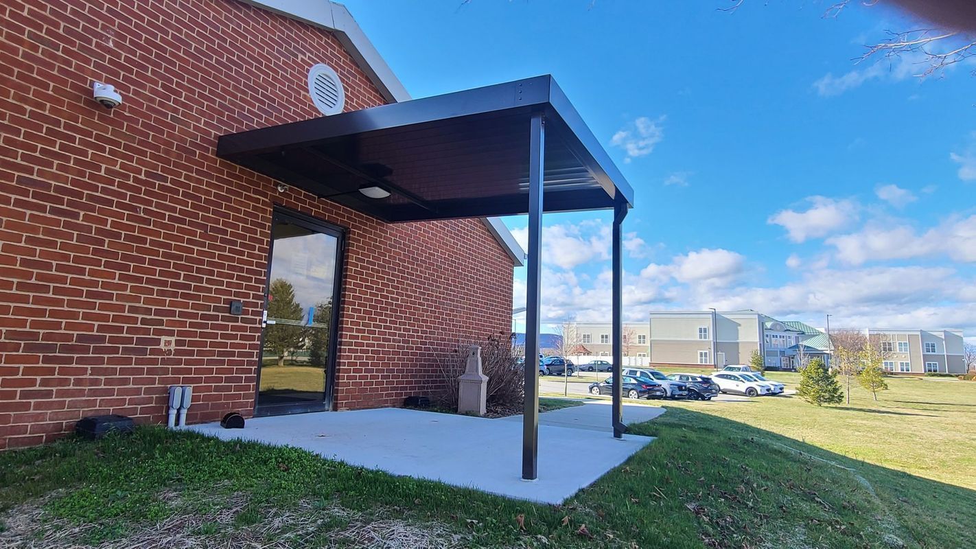Brown awning over a doorway of a red brick building on a sunny day.