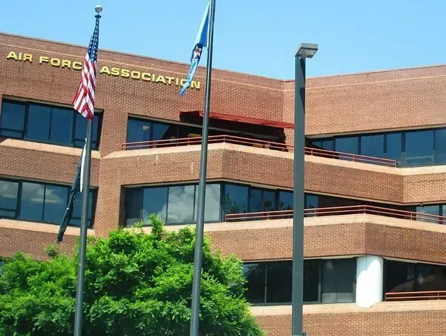Air Force Association building with American and blue flags, brick exterior, sunny day.