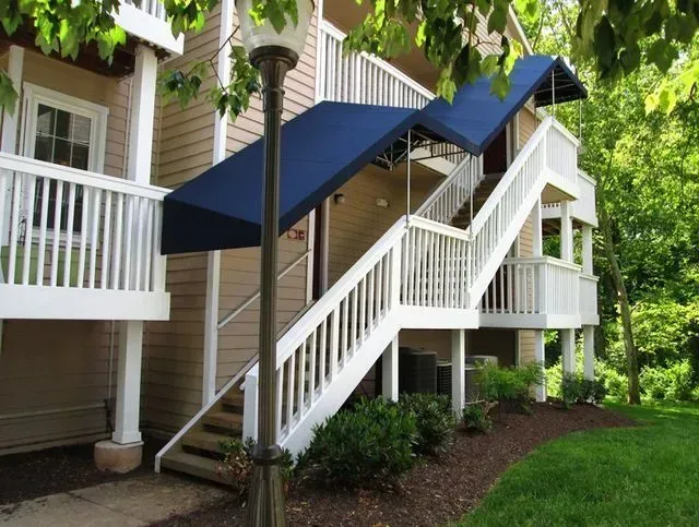 Exterior staircase of a two-story building with blue awning and white railings.