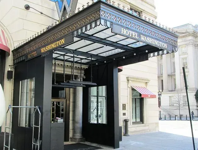 Entrance to Hotel Washington, Washington D.C.; black facade, ornate canopy, glass and metal details.