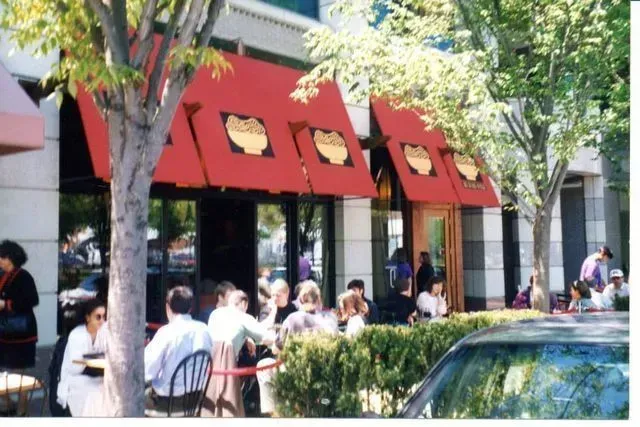 Restaurant with red awnings, outdoor seating, and people eating.
