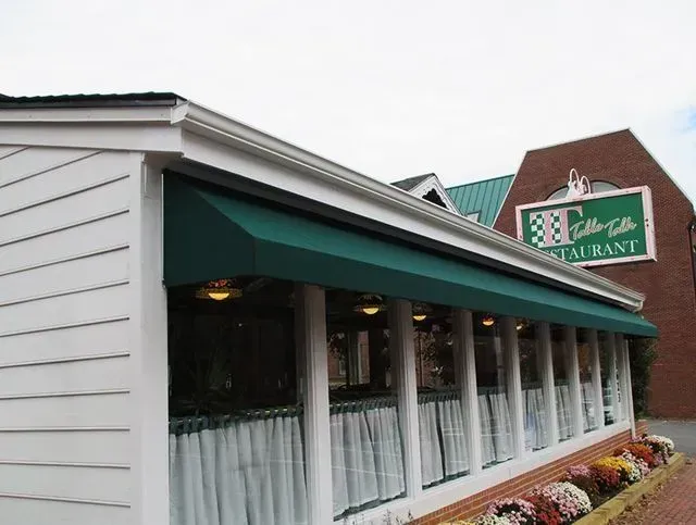 Green awning over a restaurant with a brick exterior.