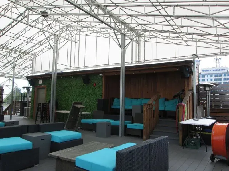 Rooftop outdoor lounge with turquoise cushions, wooden accents, and a white canopy.