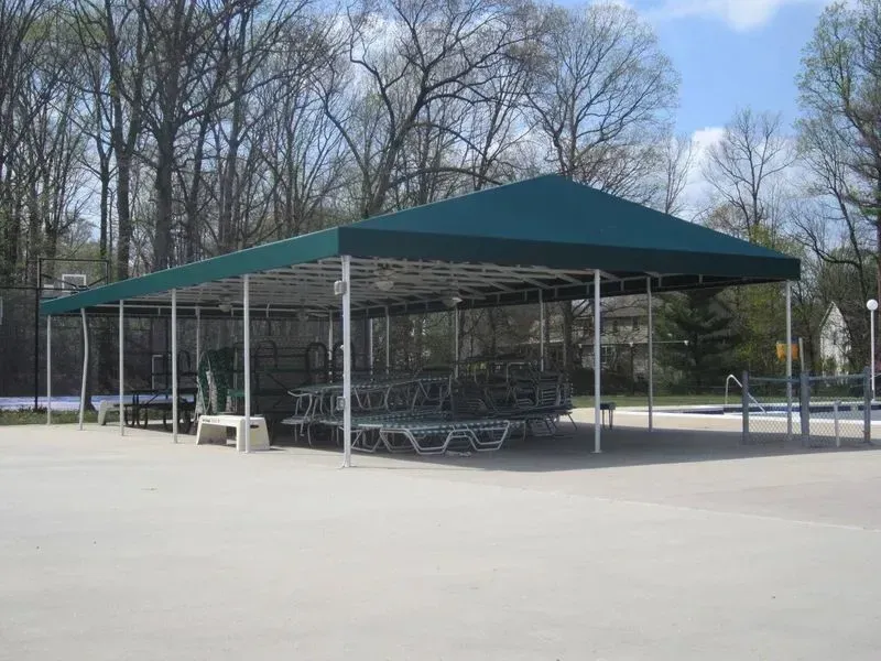 A green canopy shelters lounge chairs at an outdoor pool.