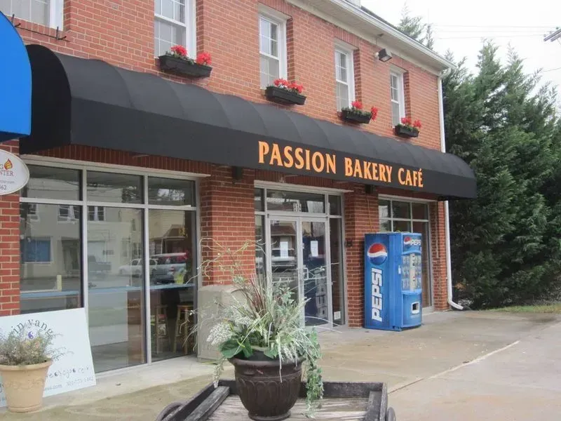 Passion Bakery Cafe storefront with a black awning and a Pepsi machine.