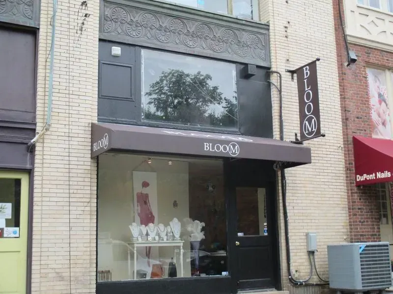 Bloom boutique storefront with awning and sign. Jewelry and clothing in window display.