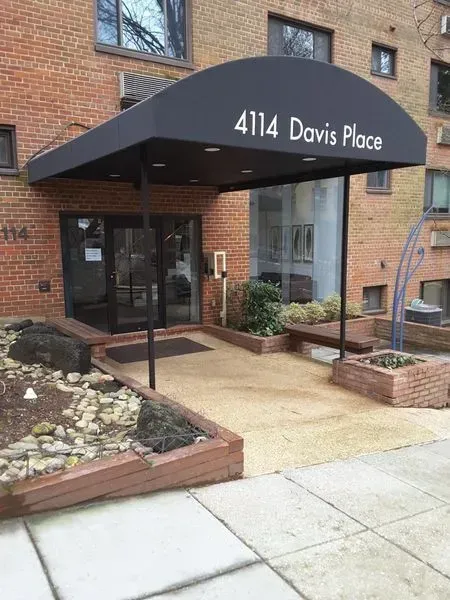 Entrance to 4114 Davis Place with black awning, brick building, and accessible ramp.