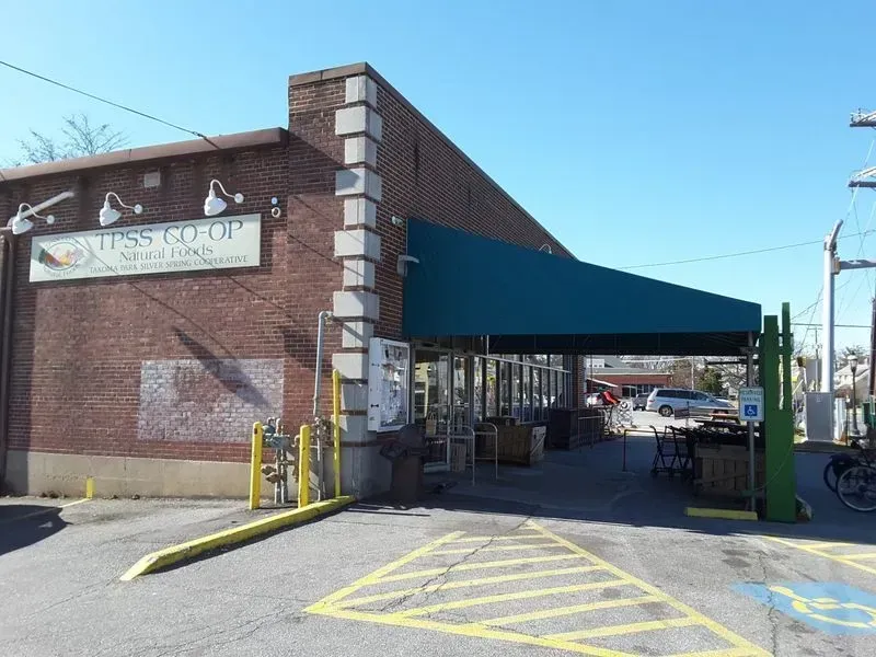 Exterior of Lessing's Co-Op, a brick building with a green awning and gas pumps.