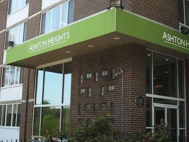 Entrance to Ashton Heights apartment building with green awning and brick facade.