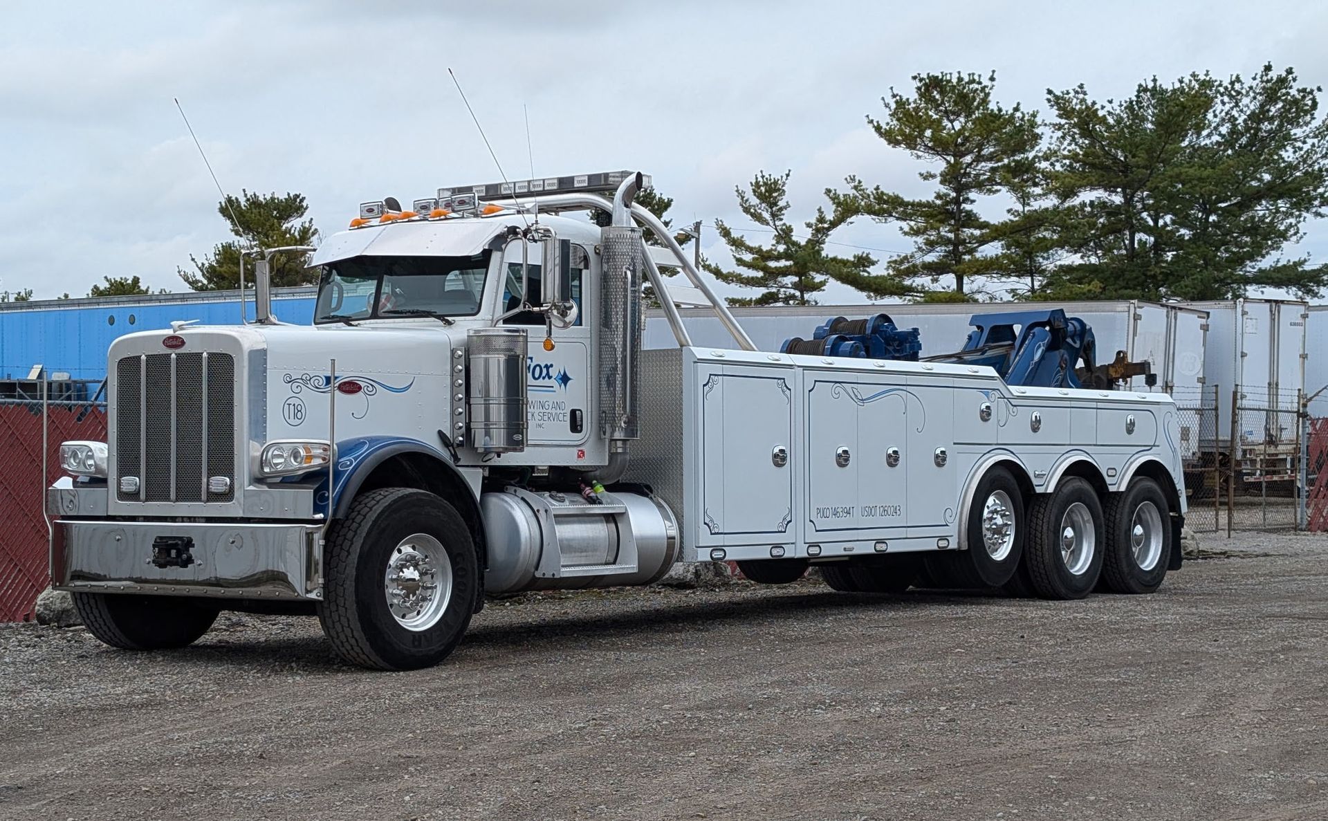 White Peterbilt tow truck parked on gravel lot.
