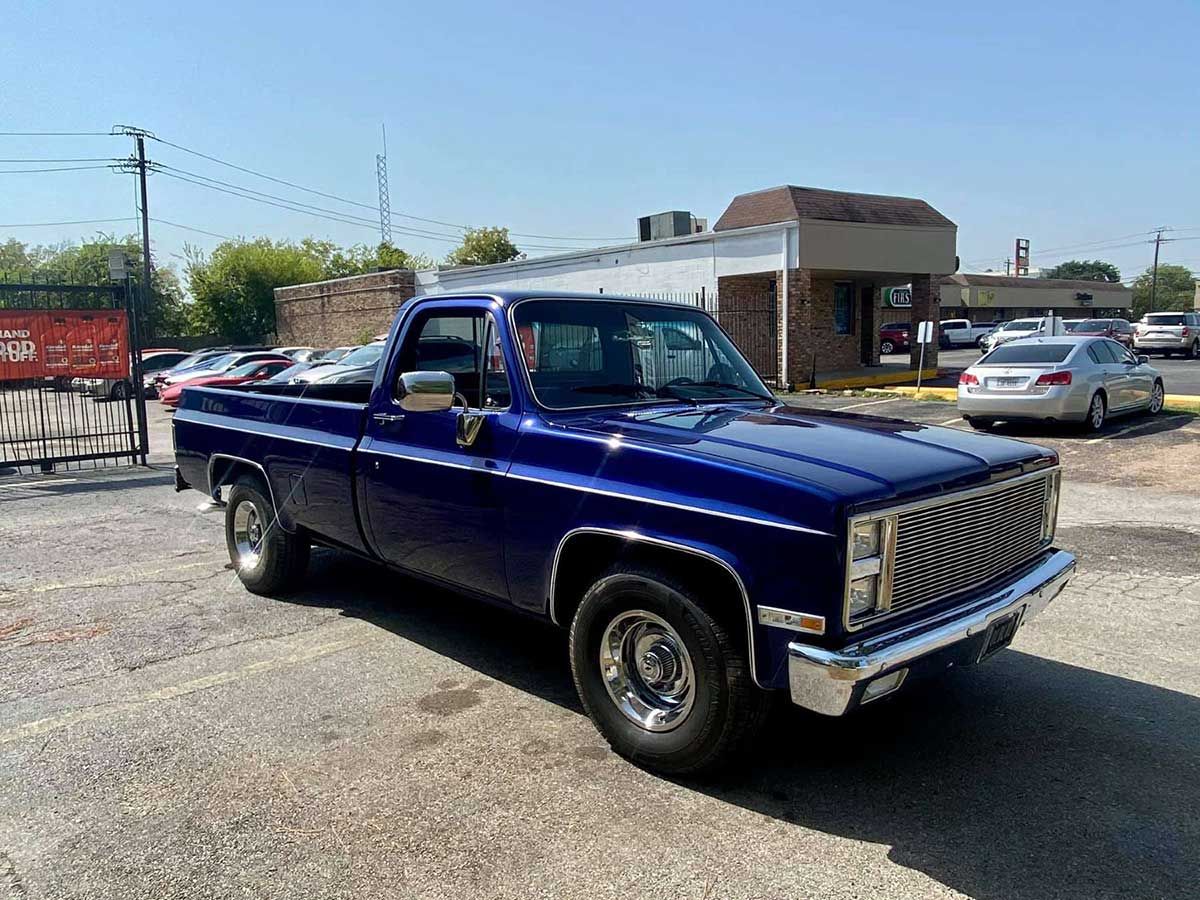 A blue truck is parked in a parking lot in front of a building.