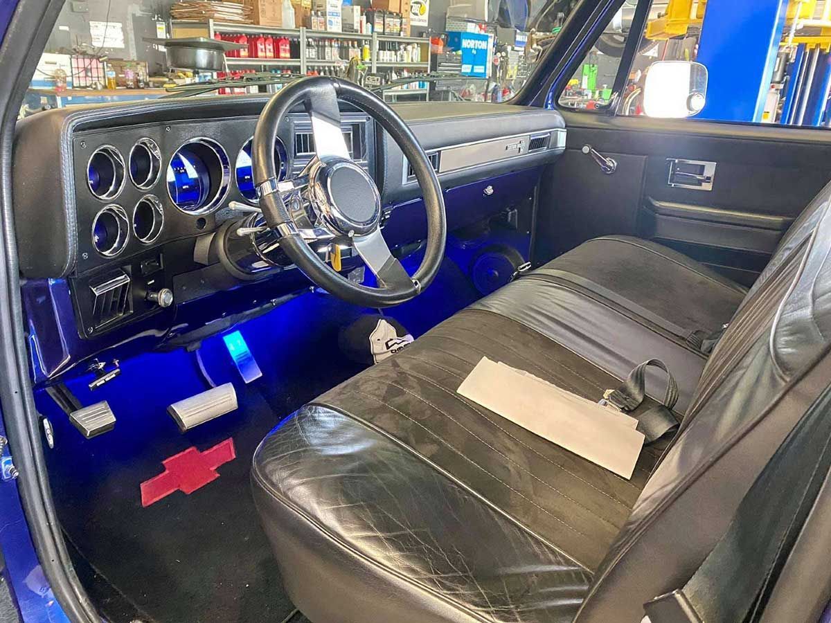 The interior of a blue chevy truck with a steering wheel and seats.