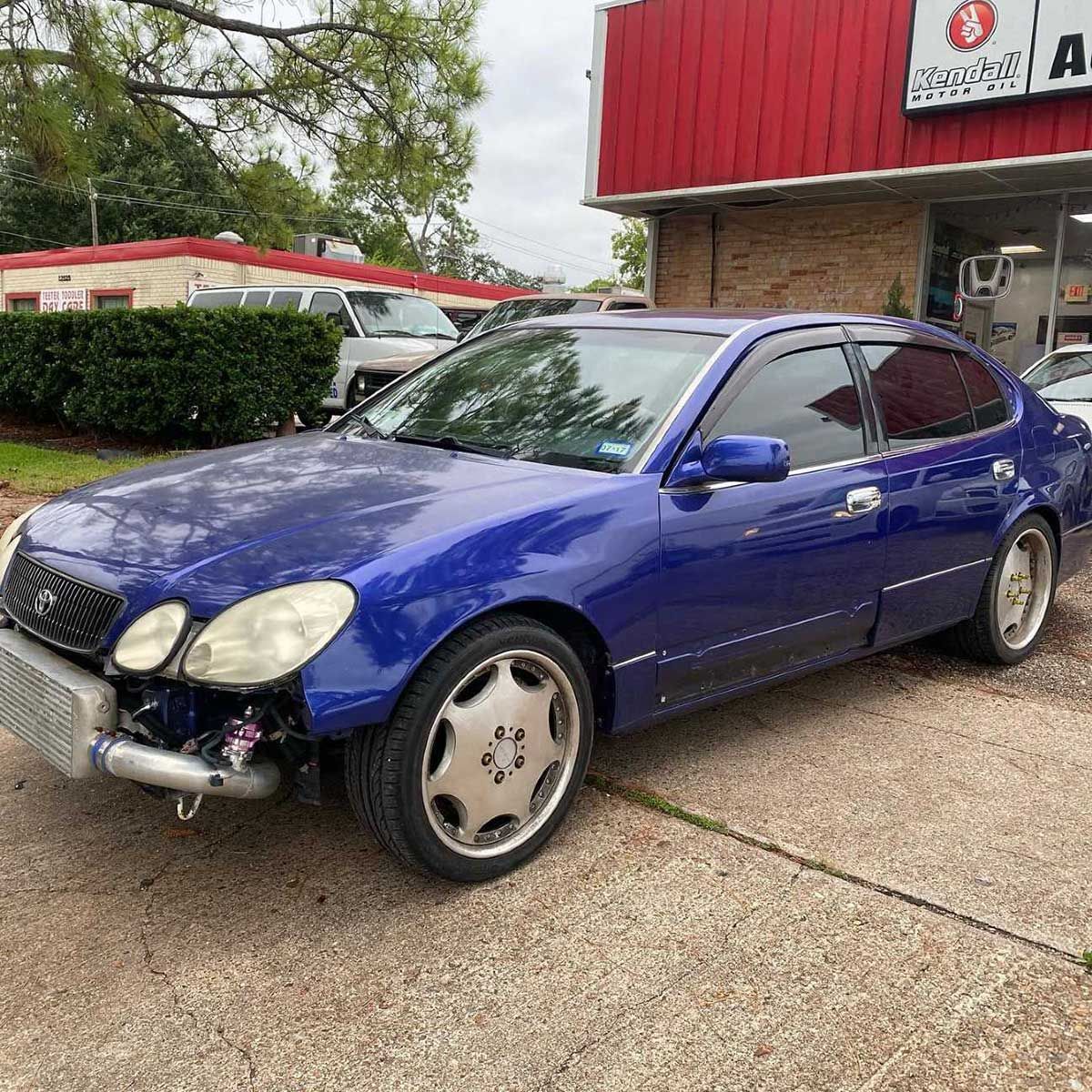 A blue car is parked in front of a red building.