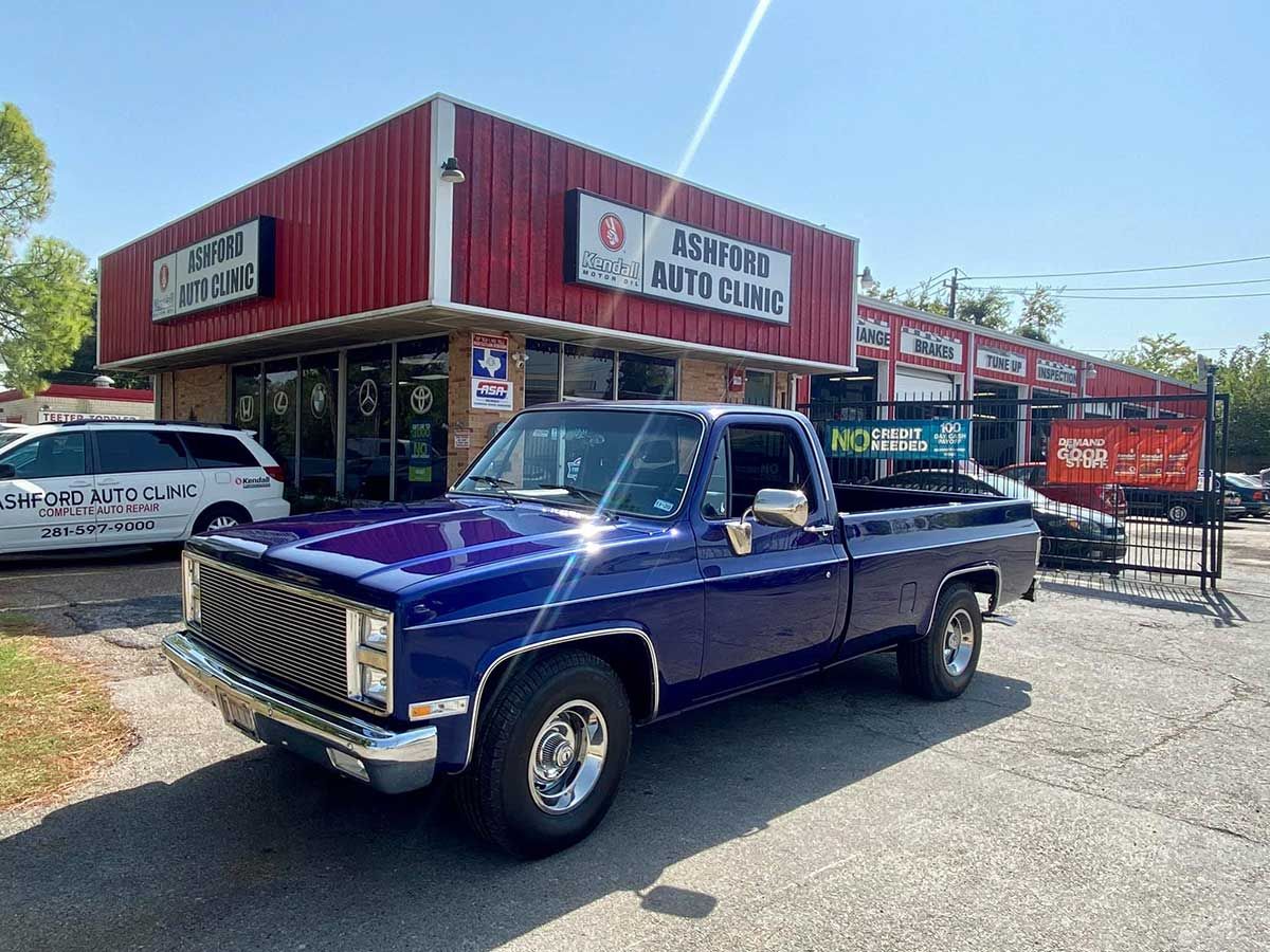 A purple truck is parked in front of a red building.