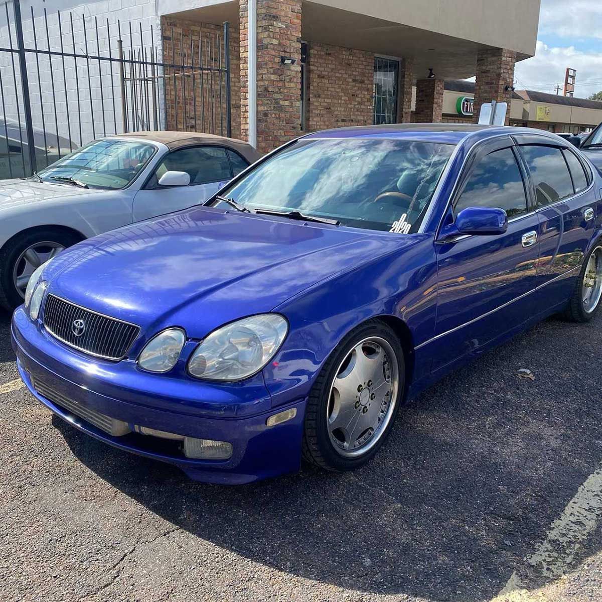 A blue car is parked in a parking lot next to a white car.