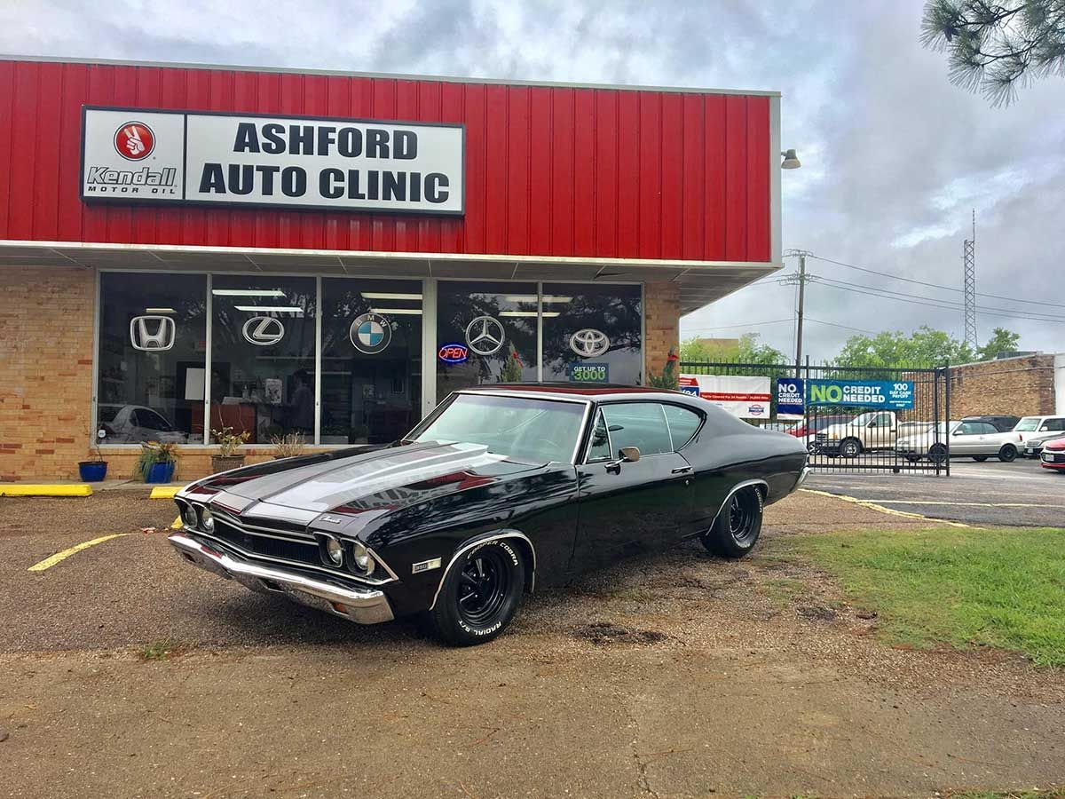 A black car is parked in front of an auto clinic.