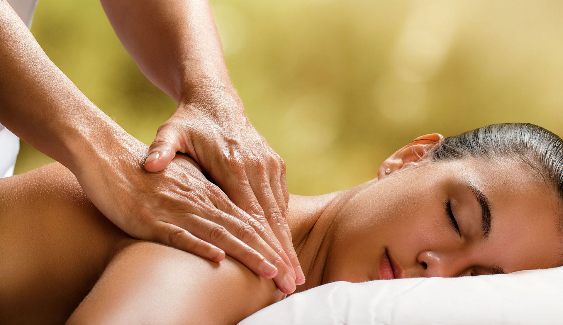 A woman is laying on a bed getting a massage.