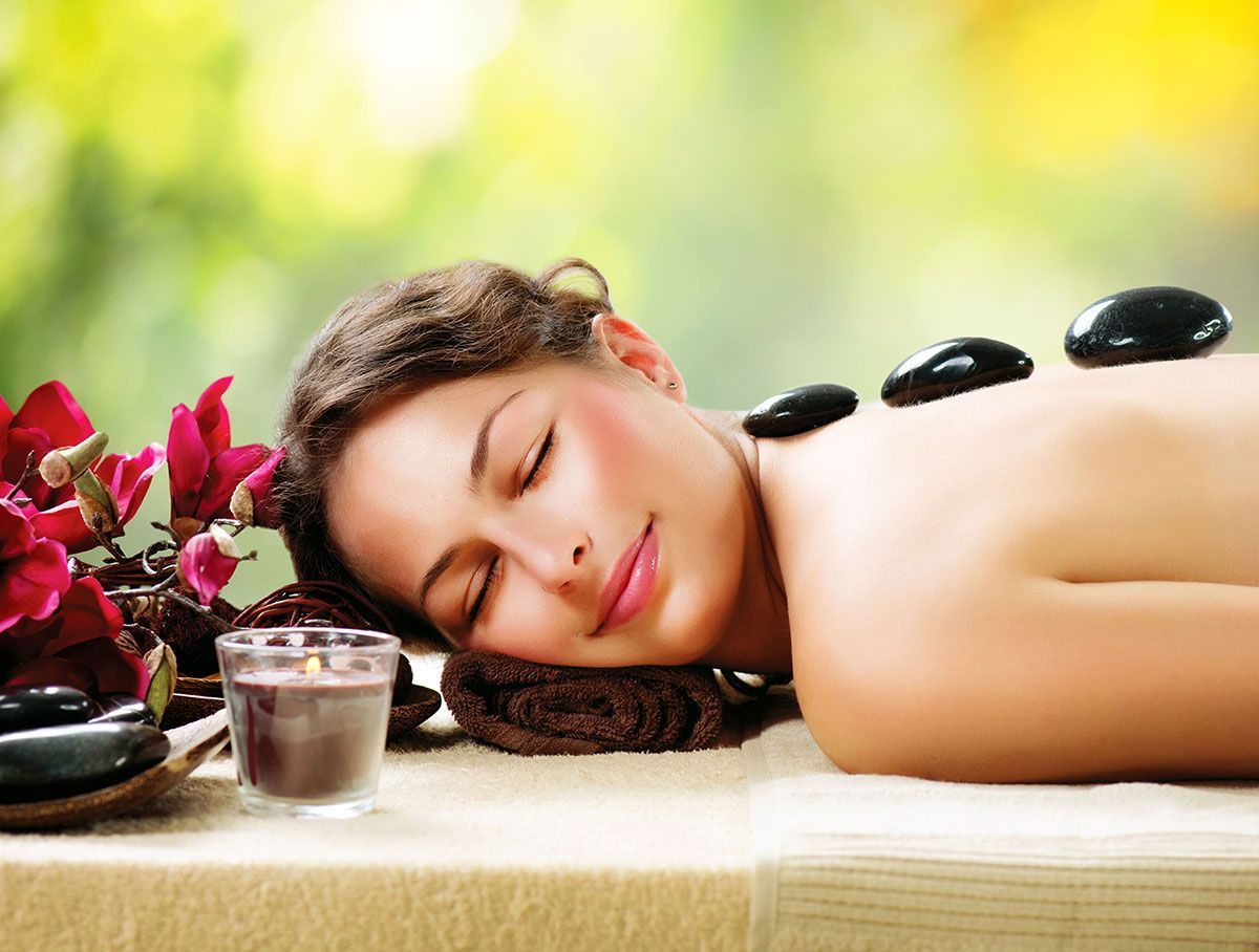 A woman is laying on a table with hot rocks on her back.