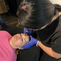A woman is getting a botox injection in her forehead.