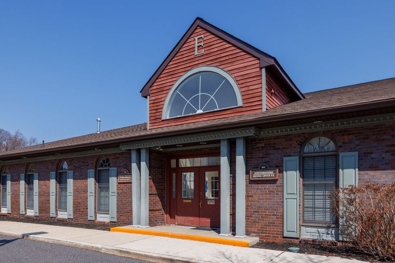 Brick building with red doors and a large arched window under a clear blue sky