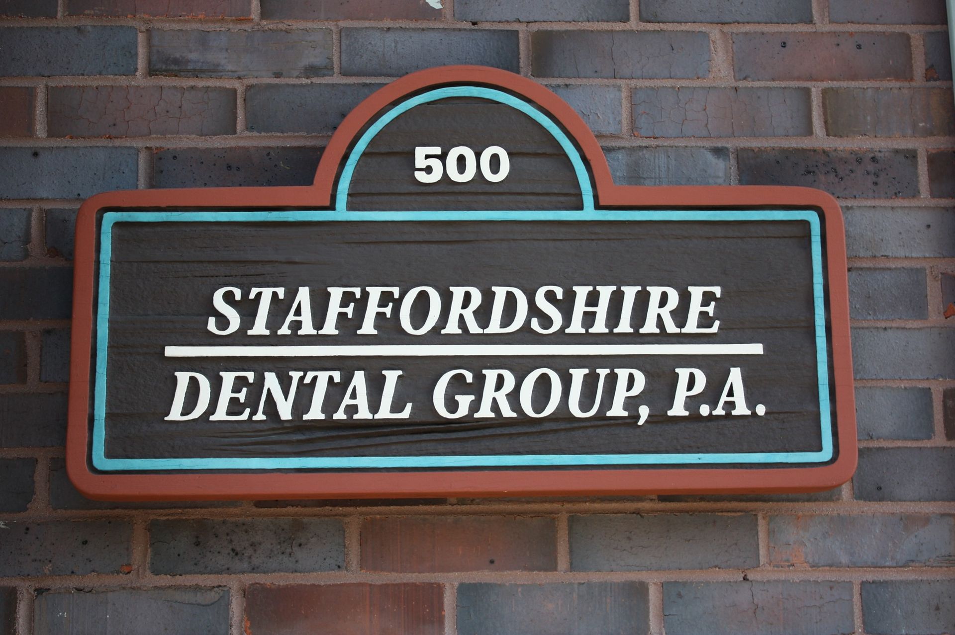 Sign for Staffordshire Dental Group, P.A. on brick wall; features address